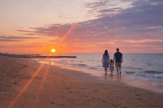 Familie spaziert am Strand bei Sonnenuntergang